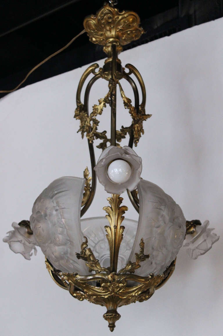 Extremely rare Chandelier in gilded bronze with 3 downswept light arms,each ending in a stylized  frosted petal crystal bulb enclosure  and joining at the bottom to form a base supporting 3 more lights,each behind a large and thick hand pressed