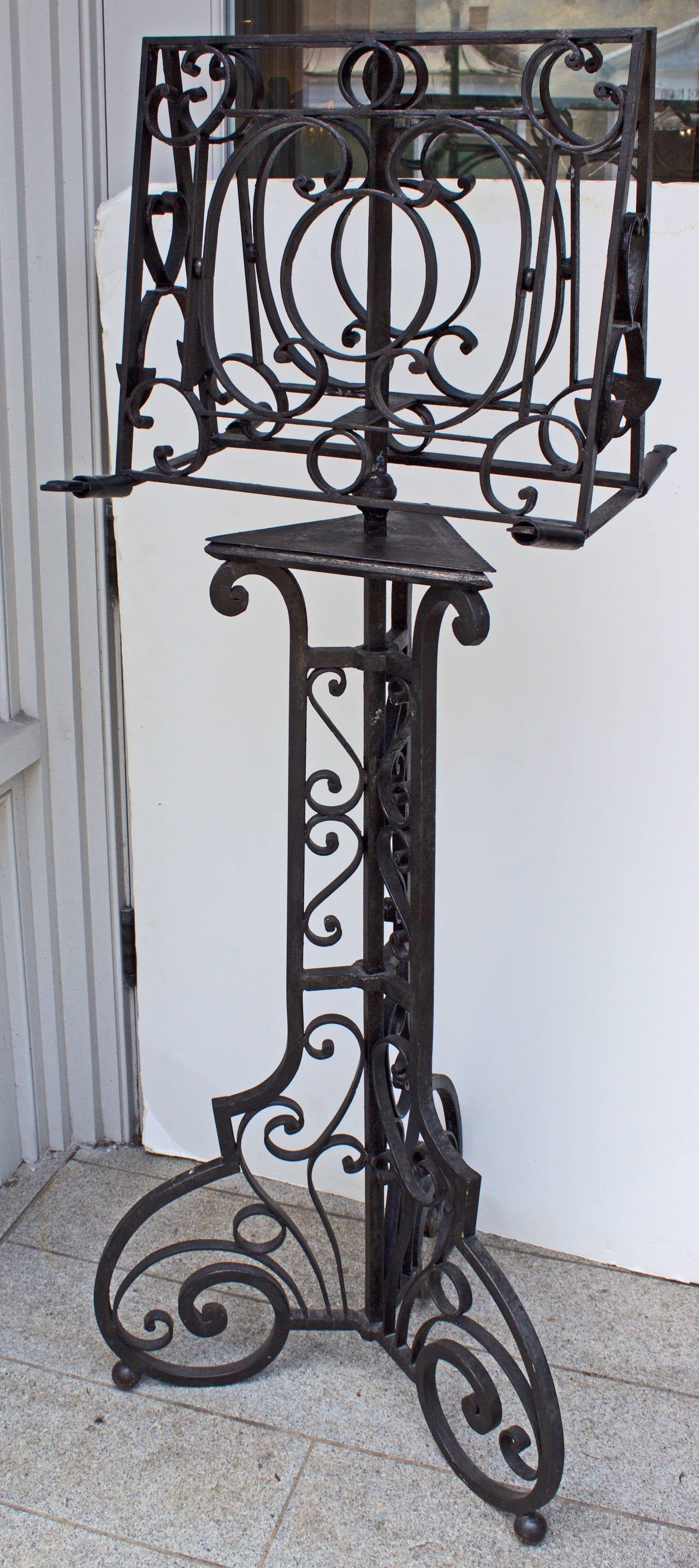 Entirely original hand-forged lectern with an exceptional quality open work decor of scrolls and interlaced design on top, on the central support and on the tripod feet terminated by small metal spheres. It is of course double sided for books or