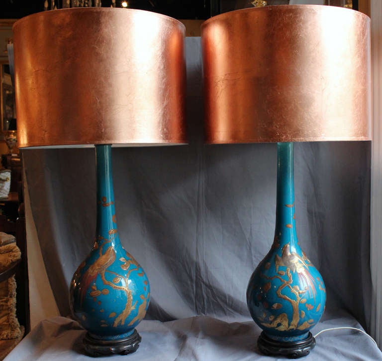 A lovely pair of porcelain vases with long necks, elegant lines and covered with a teal blue glaze color. Embellished all around by a handraised paste décor of birds and foliage painted in gold and red bole, in the ornamental Aesthetic Movement