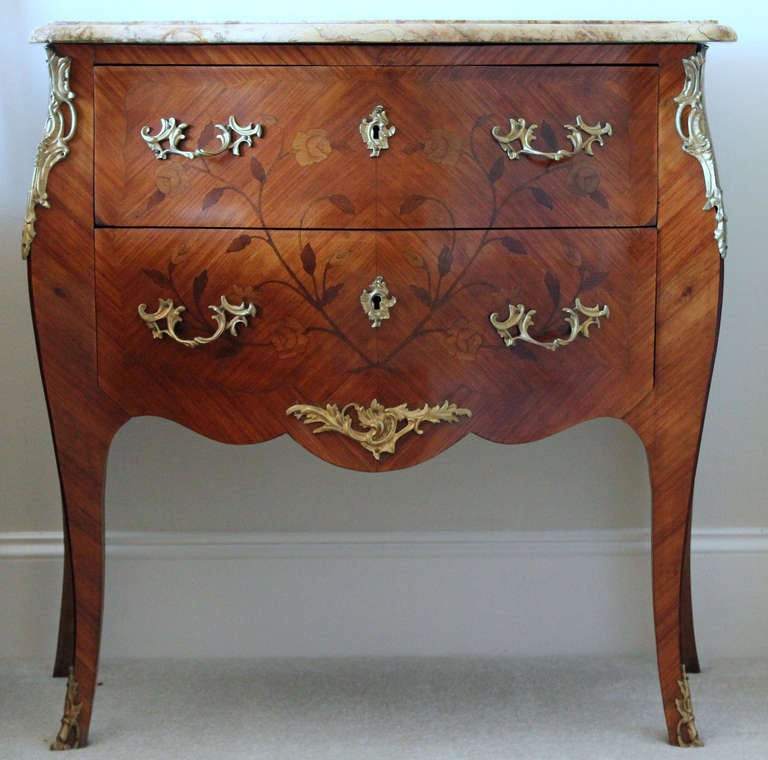 A fine Parisian Louis XV style tulipwood veneer chest with well executed floral marquetry in exotic woods on the three bombes sides. This commode is bronze trimmed, has two 