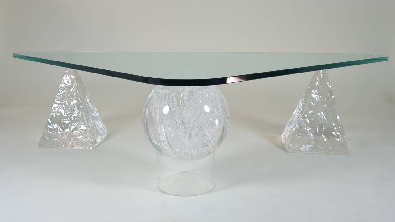 A large fractured Lucite sphere is the centerpiece of this cocktail table base flanked by a pair of textured Lucite pyramids. Heavy glass triangular top is 3/4" thick. Excellent condition. A truly spectacular table.