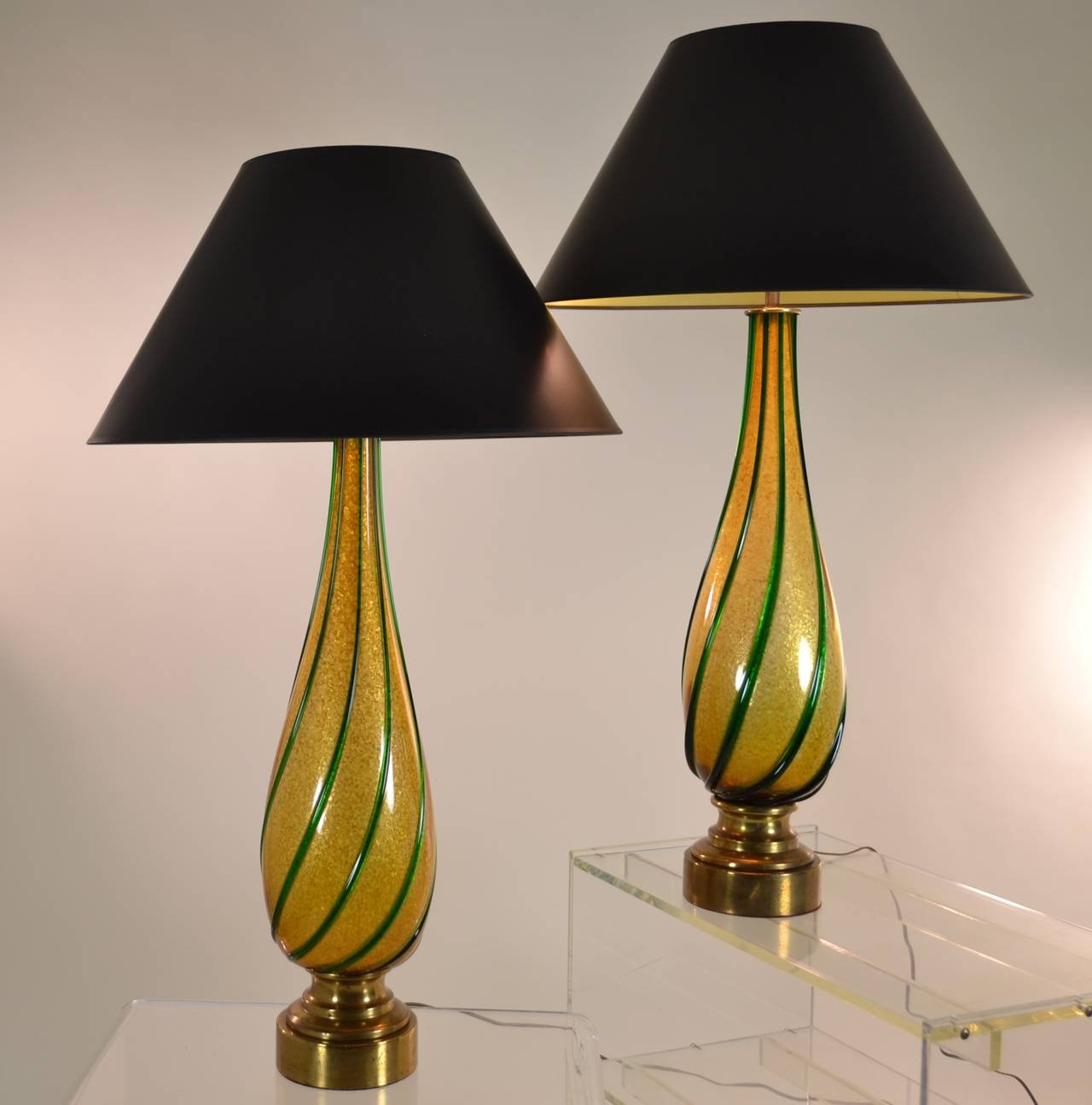 Heavy gold flakes in the glass give the lamps a beautiful warm glow accented with applied green glass piping. A nice vintage pair with new wiring and shades, Italy, circa 1950s. Dimensions: Height to top of finial is 38