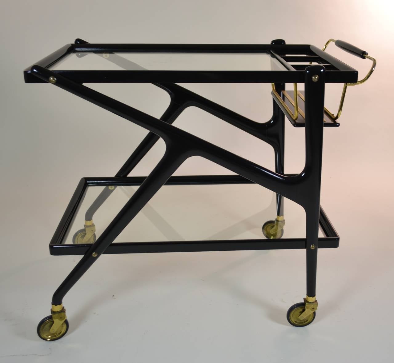 A handsome Cesare Lacca cocktail cart in high gloss black lacquer with polished brass details and including Classic bottle rack with three slots. In excellent condition.