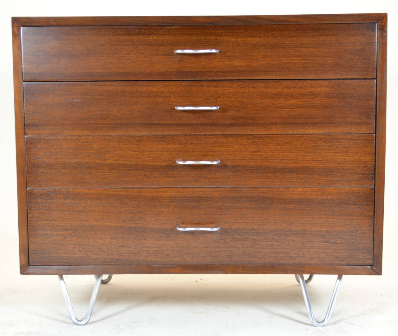 Beautiful walnut chest newly refinished with original hairpin legs and "M" form handles in brushed steel. Excellent condition. Herman Miller label with printed George Nelson signature in top drawer.