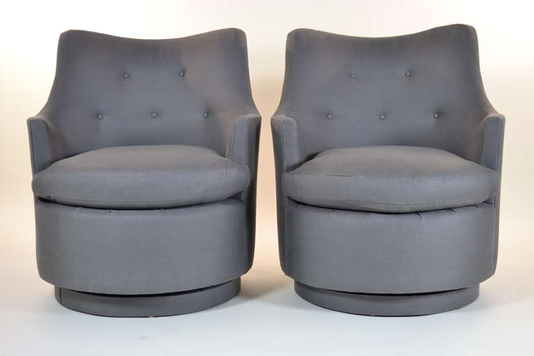Newly upholstered pair of swivel chairs designed by Edward Wormley for Dunbar, circ 1950s. Upholstery cover is grey linen. Disc base is also covered in  fabric.