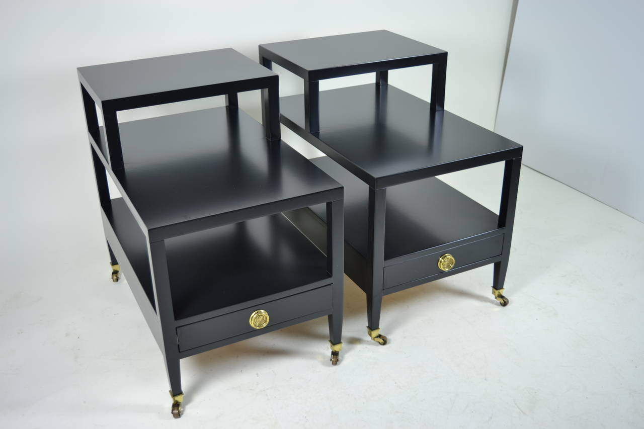 Handsome end tables by Baker Furniture, newly lacquered in satin finish black. Solid brass casters and pulls. Each table features a single drawer and 3 stepped levels. Heavy, very good quality. Excellent condition.