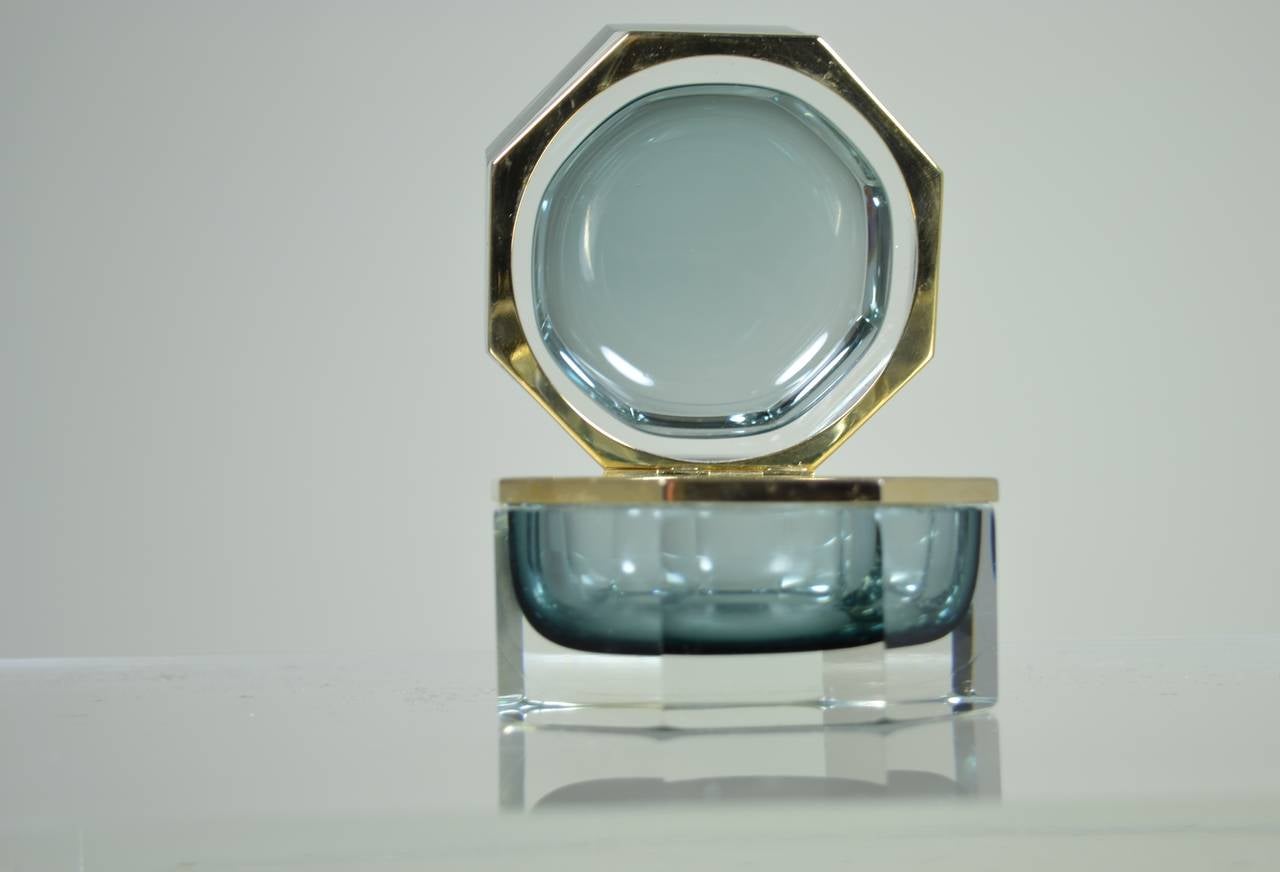 Heavy glass lidded box with gold-plated bezel, clear glass octagon with interior grey oval hollow. Very elegant and in pristine condition. Maker's mark stamped into metal.