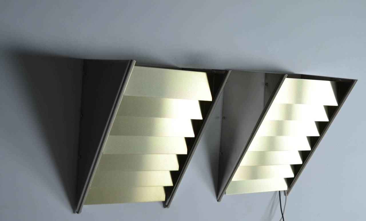 Brushed brass louvers in a polished steel fixture. Can be mounted as a down light or an up light. Found new in box, never used. Take up to a 100 watt bulbs. Single bulb per fixture.