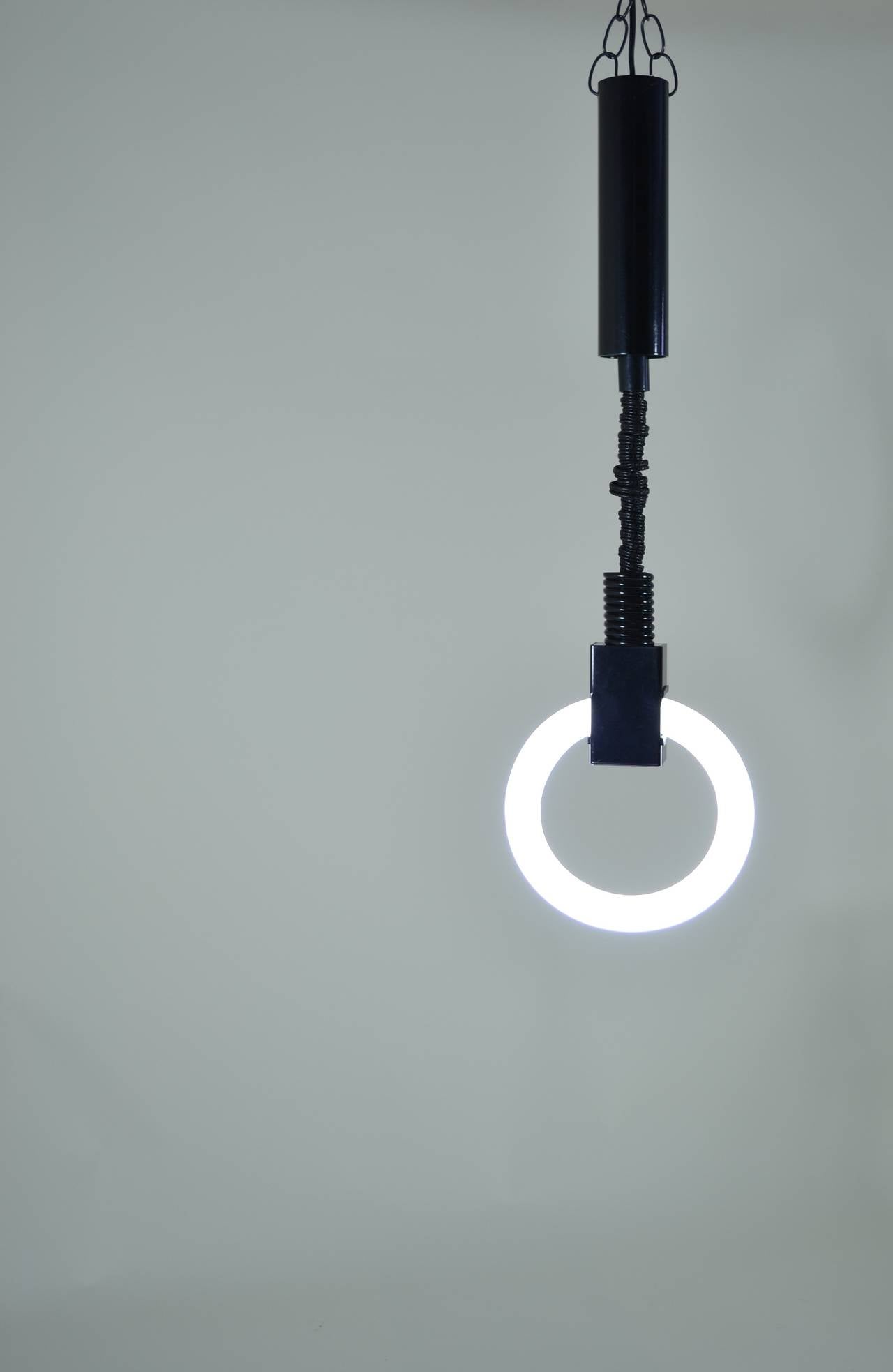 So cool. Vintage pendant with neon tube ring. Black powder coated metal and a nylon sleeve covering the chain for the fixture which holds suspended and standard neon ring. Very sculptural and actually gives a nice light. We have three available.