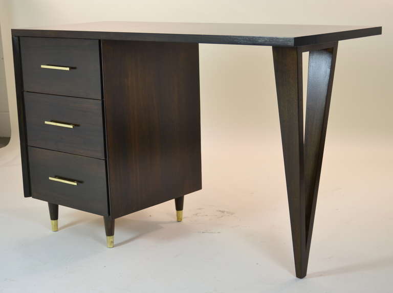 Modernist desk by John Stuart with three side drawers and interesting sculptural form. Totally restored with deep coffee stain and polished brass details.