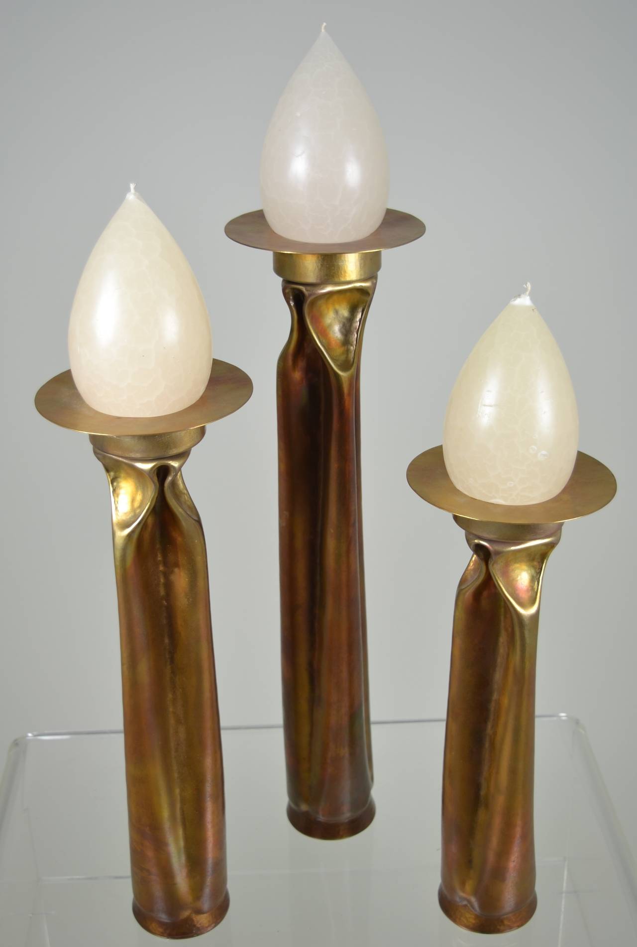 Amazing opalescent finish on this set of three-tiered candlesticks, copper oxide with brass candle dish. Exceptional examples of works by Markusen, well known for innovative metalsmithing, recognized by museums around the world. Each candleholder is