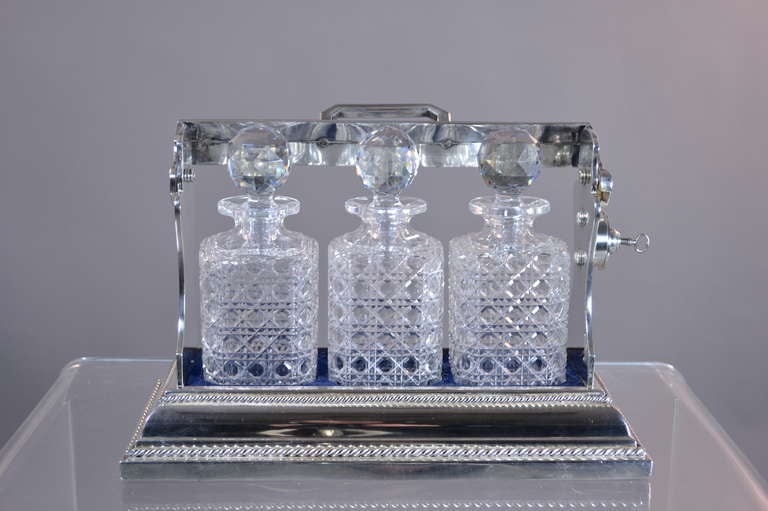 FIne Sheffield silver plate tantalus made circa 1910-1920 by the reknowned English silversmith Mappin & Webb. Locking mechanism on side releases the three cut crystal decanters with the turn of a key. Decanters are fitted into original velvet lining.