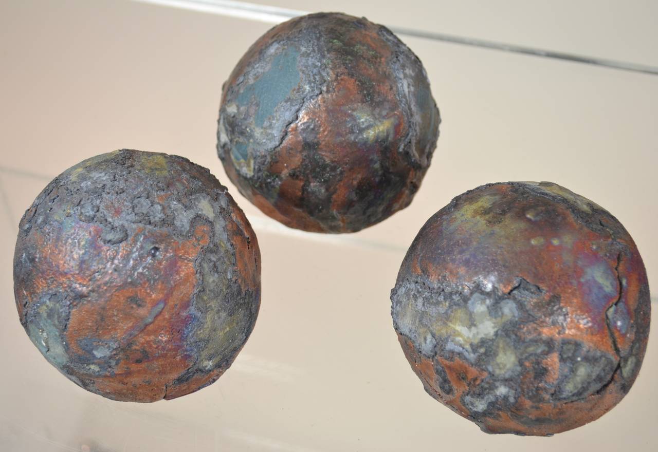 Wonderful Brutalist texture and coloration. A set of three in ceramic spheres, combining gloss and matte glazes. Each with a flattened base for easy display and individually crafted with handmade variations. And each has an interior bead making a