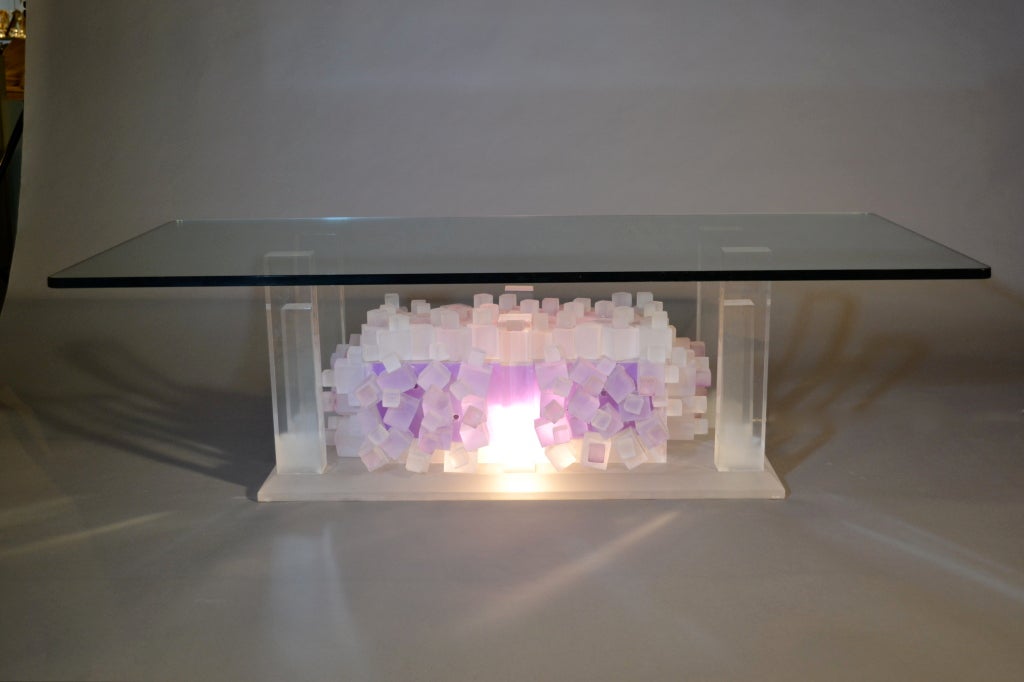 A really unusual sculptural cocktail table that softly glows from the interior of tumbled lucite blocks. A heavy glass top is supported by clear lucite columns, all arranged on a heavy frosted lucite base. Very dramatic. The base is 34