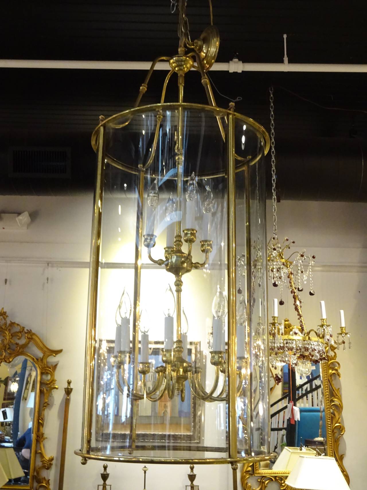 Large vintage brass double hanging lantern, of typical cylindrical form with two tiers of lighting, the top tier with four lights, the lower tier with eight lights, surrounded by four large curved glass paneles.