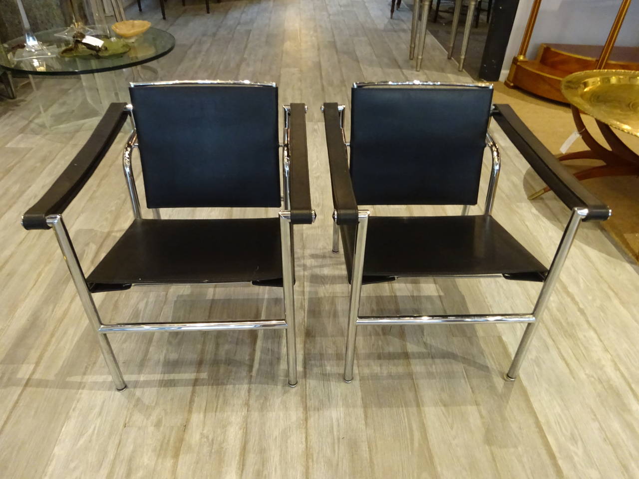Pair of Le Corbusier suspension club chairs, each one of typical form of chrome and leather.