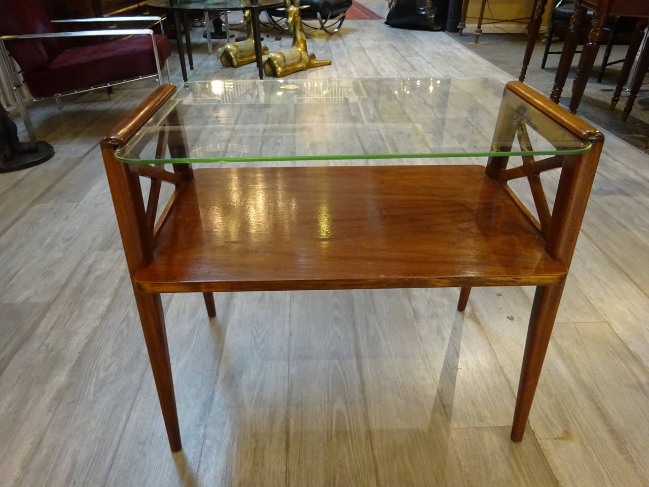 Pair of end tables in the manner of Jacques Adnet, each one of rectangular form with inset glass top glass shelf, supported by flanking 