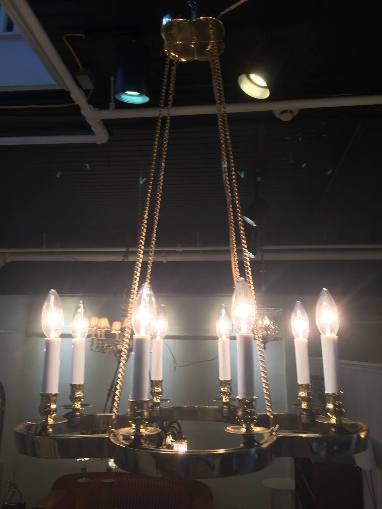 Brass chandelier in the manner of Tommi Parzinger, with signature brass medallion canopy with four brass chains supporting eight-light brass clover shaped platform, great diminutive size. Recently professionally polished and rewired.