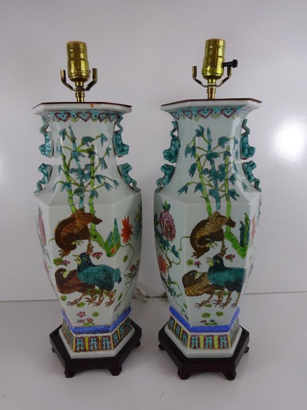 A pair of Chinese Export Famille Verte vases, now as lamps, each one of hexagonal from decorated with birds and flowers, raised on a conforming carved wood stand. Recently rewired.