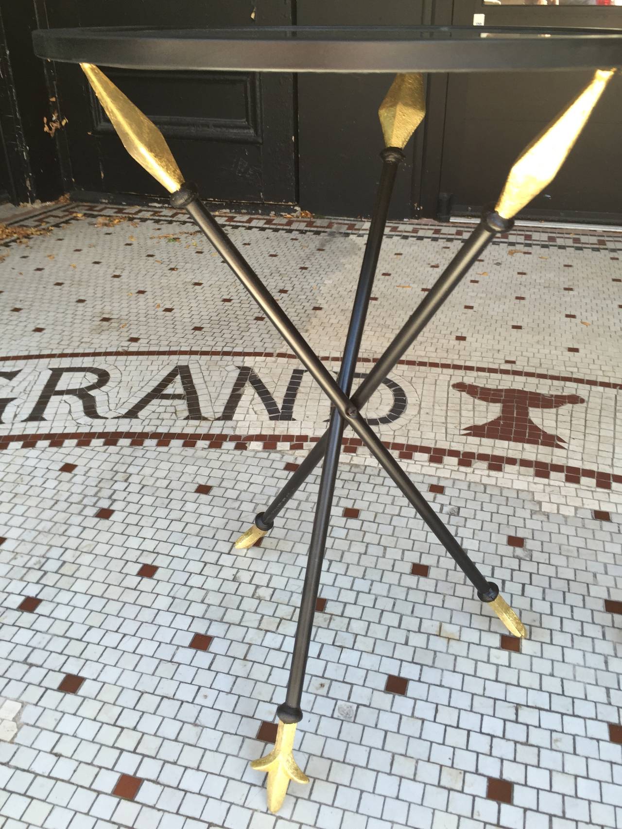 1950s French Gold Leaf Arrow Tables, Each one with inset black glass tops, supported by three gilded arrows