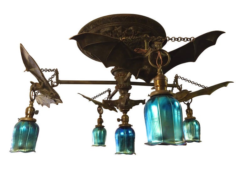 A very unique Austrian bronze bat motif chandelier with five blue aurune Steuben style glass shades. Bats suspend from chains and have glass eyes.
