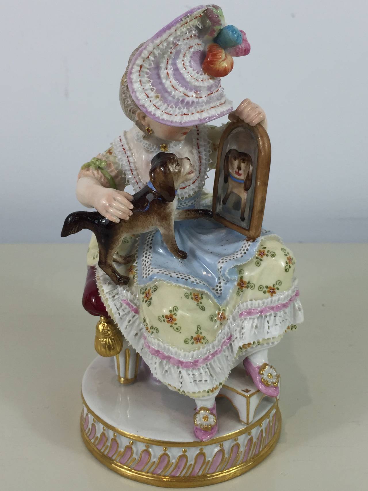 Meissen Girl with Mirror and Dog, of exceptional quality and condition. The seated lady with her dog on her lap, with mirror at hand. Blue under glaze crossed swords with painters mark of 