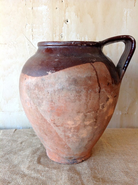 This beautifully glazed water jug from the Umbria region of Italy has a lovely red glaze atop the natural terra cotta.  The oversized handle adds a rustic charm to this handmade antique pot.
