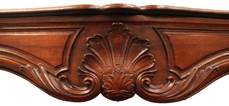 An 18th century Italian walnut fireplace mantel with a hand-carved center shell motif.