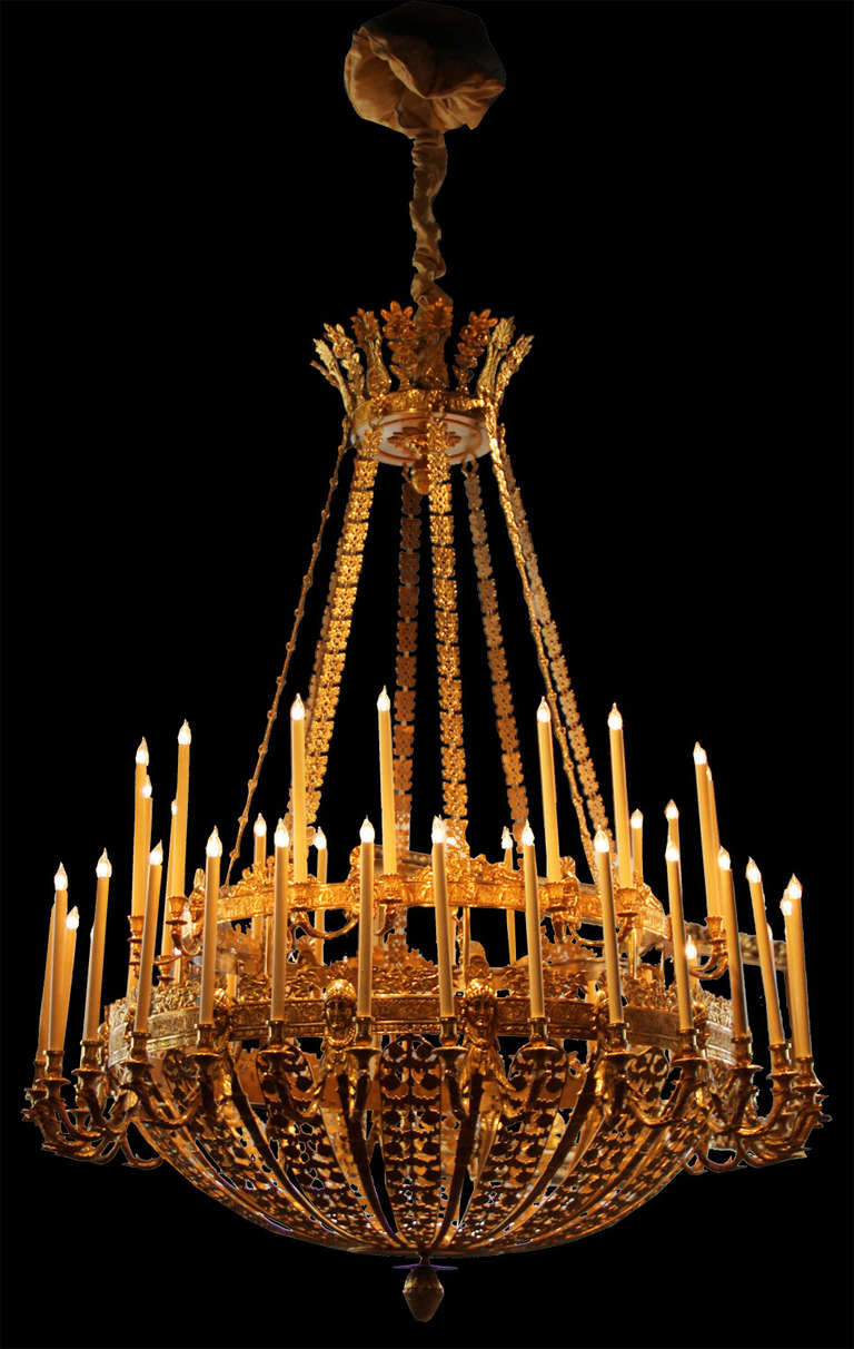 A palatial 19th century French Empire bronze Doré, forty-six-light chandelier, with thirty-two lights on lower tier and sixteen lights on the upper, the whole embellished with a regal corona above a tent of eight floral motif tendrils and accented