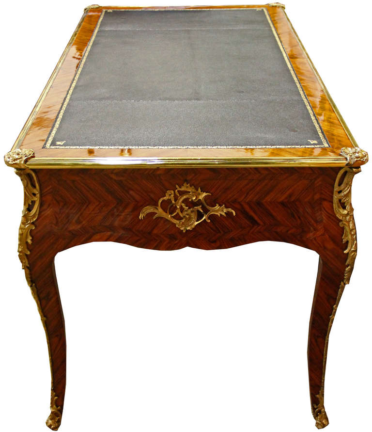 A sophisticated 18th century French Louis XV kingwood and ormolu bureau plat desk, with one long drawer flanked by two shorter drawers, with a later black leather and gold embossed writing surface and raised on cabriole legs terminating in brass