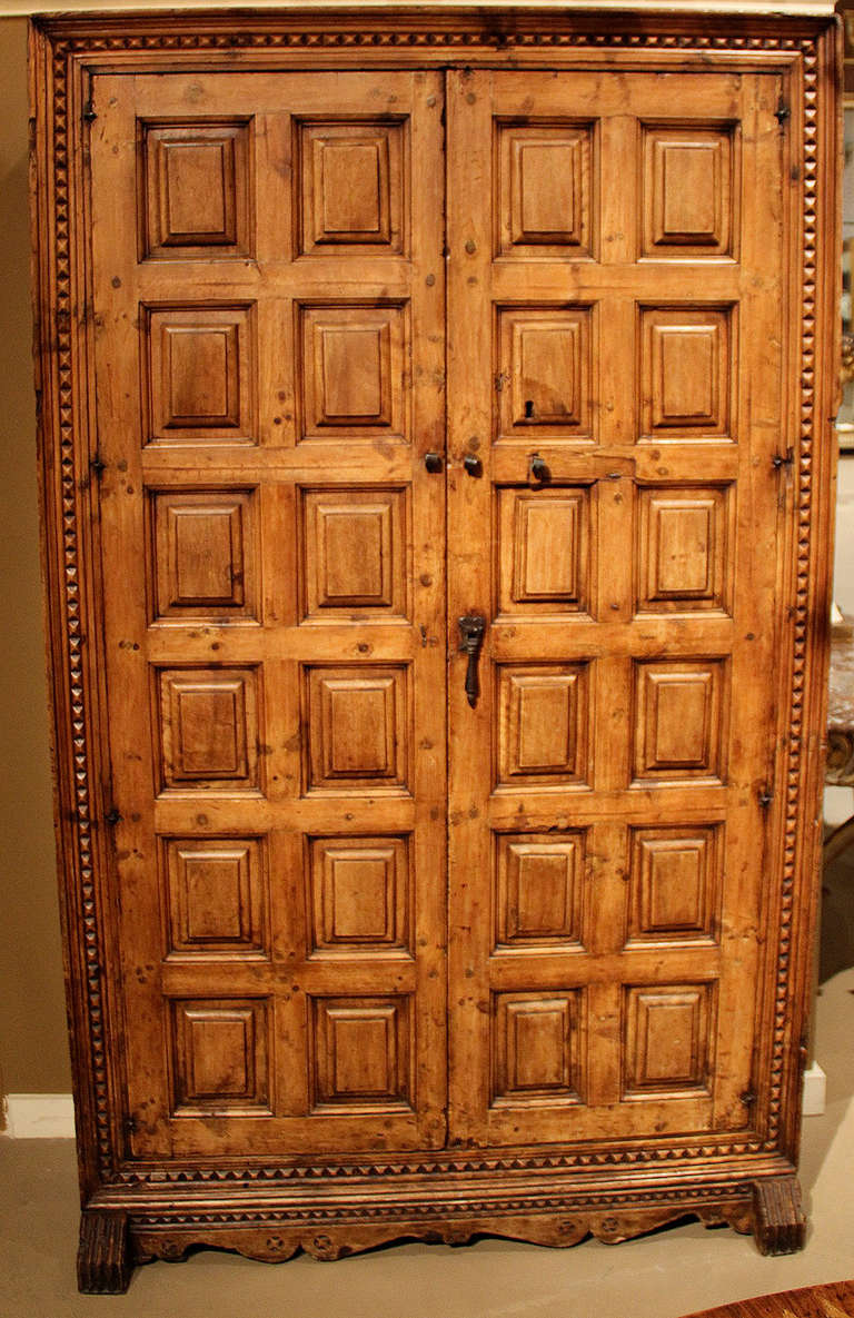A late 18th century Spanish carved elm armoire with its original iron hardware intact and decorated in a simple "waffle" pattern of hand-carved raised panels.