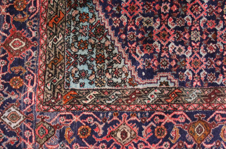 Vintage Persian wool rug, centered with a diamond medallion and woven in various vivid tones of red and blue along with a spectrum of pastel tones.