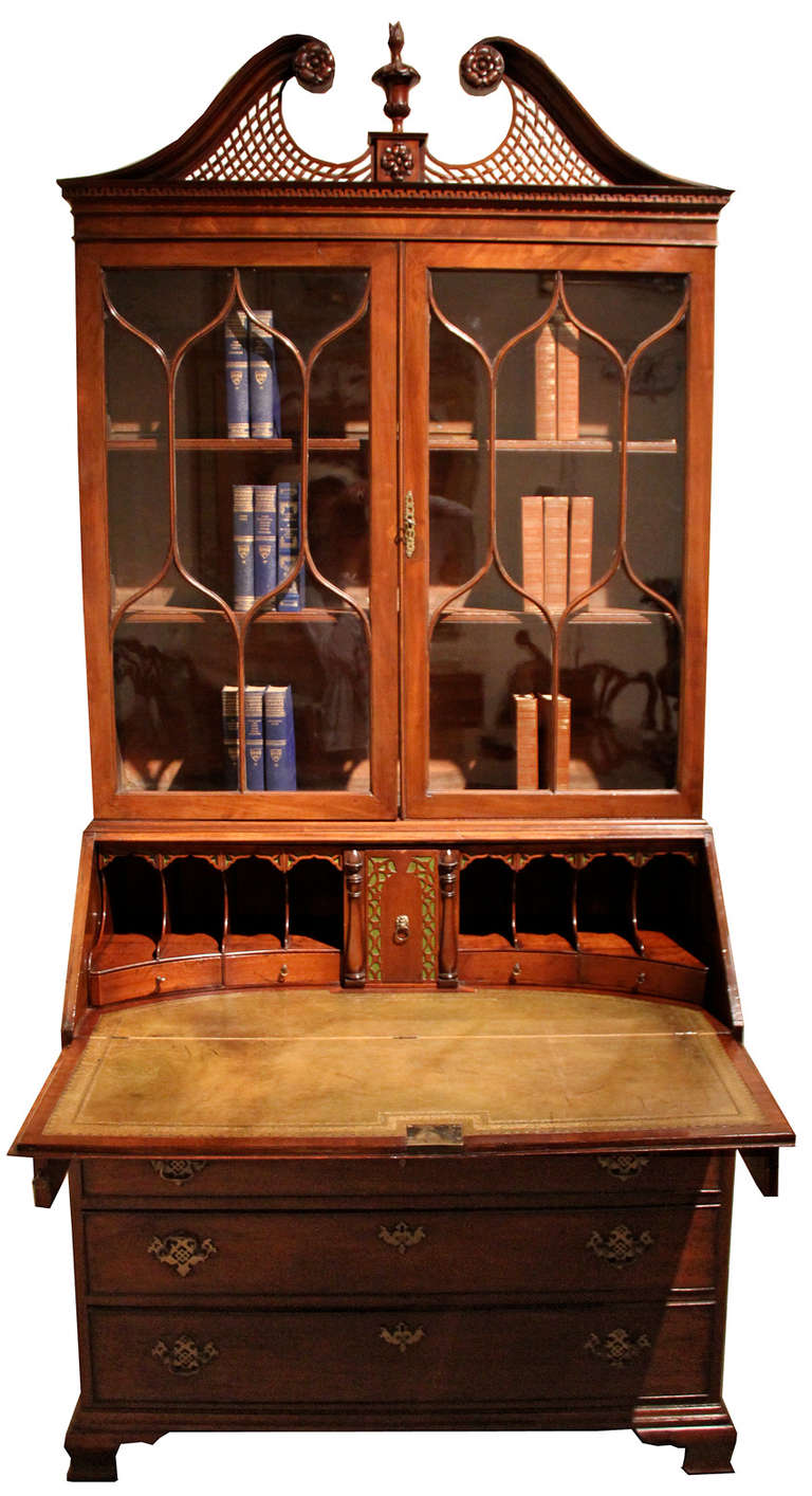 A late 18th century English George III mahogany Bureau bookcase (secretaire) with fretwork open swan neck pediment, centered by a shaped finial, above a pair of glazed doors, slant front enclosed leather writing surface, fitted drawers and cubbies