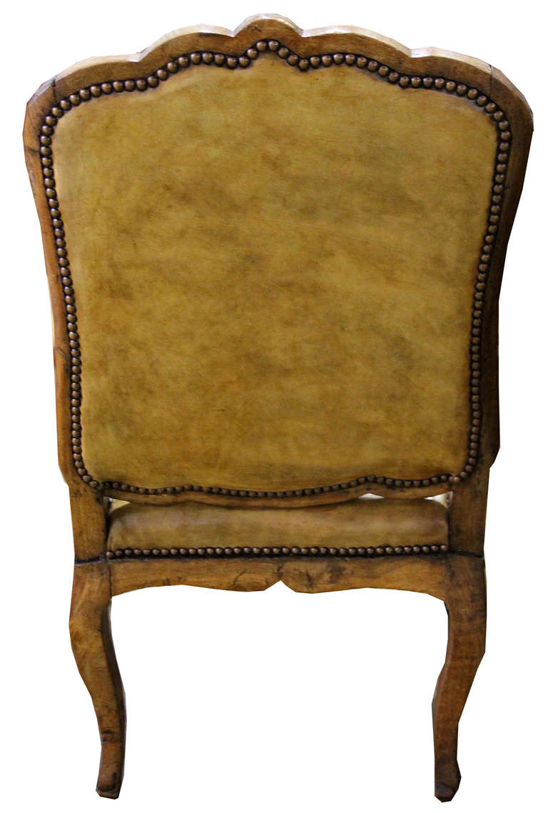 An 18th century Italian Louis XV beechwood armchair, the arms with manchettes and the whole raised on cabriole legs, the seat and back now upholstered in C. Mariani cartouche-stitched and glazed antiqued leather and accented with nail head trim.