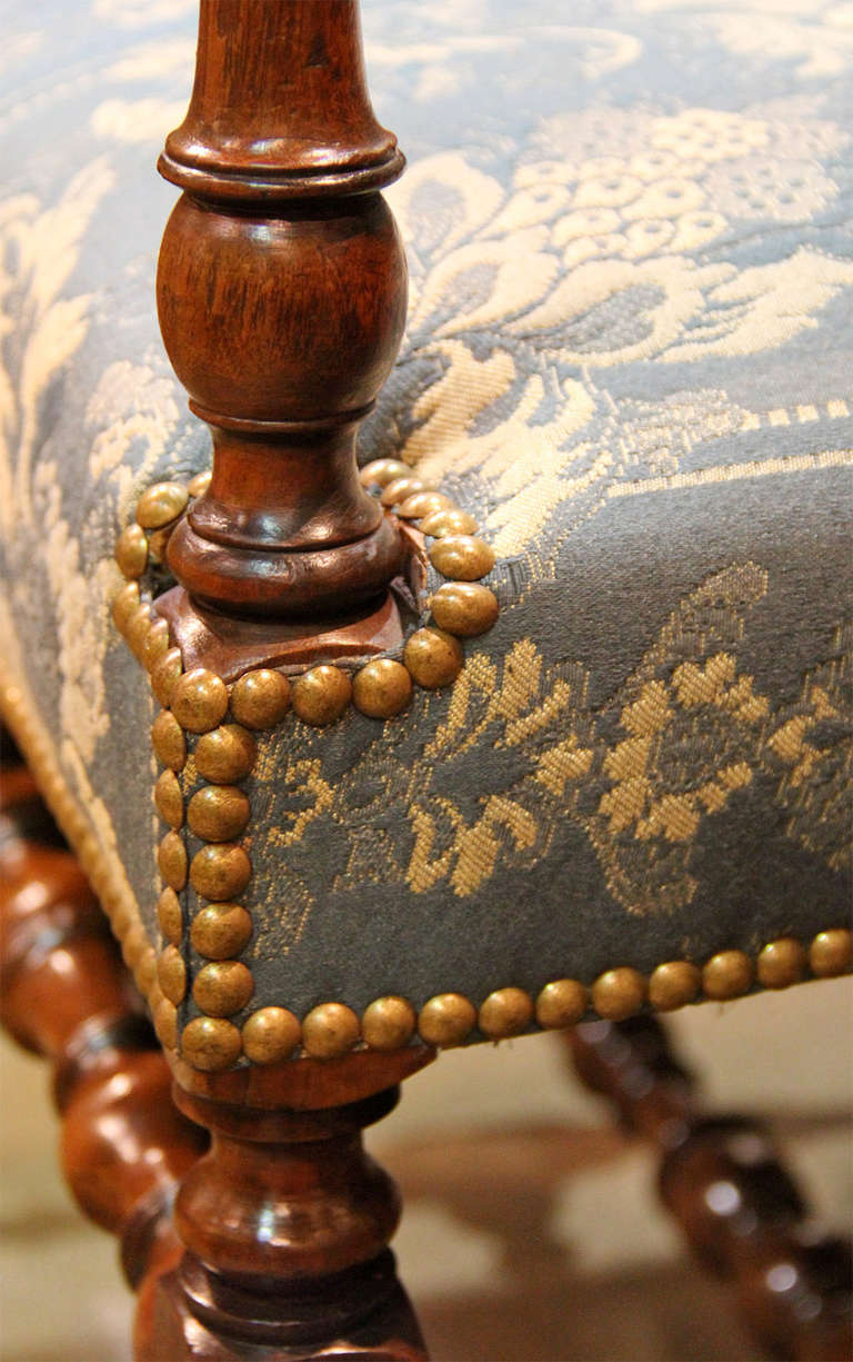 A Pair of Early 18th c. French Walnut Louis XIV Fauteil Armchairs, one for the master of the chateau and one for the lady, both with bobbin and spindle carved legs, arm supports and stretchers both connecting the two front legs as well as an