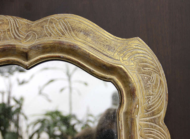 A mid-20th century shaped parcel giltwood and white polychrome mirror.