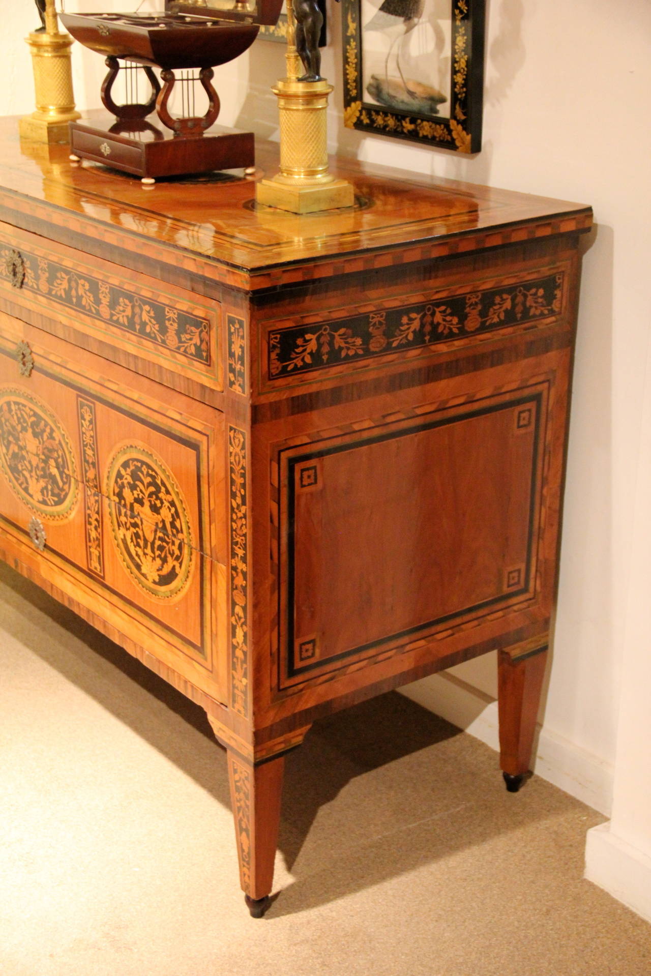An important 18th century Italian Maggiolini commode, fitted with one narrow and two large drawers sans traverse, the whole embellished with exquisite satinwood, boxwood and rosewood marquetry of neoclassical motifs with conforming inlaid top, the