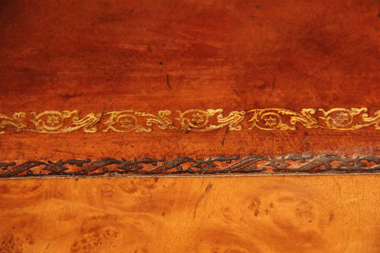 A 19th c. English Regency Burl Walnut Desk, the top featuring a later C. Mariani hand-embossed gilded leather writing surface, 7 functioning drawers, one long center drawer and 4 smaller flanking drawers and a double faux drawer front opening to