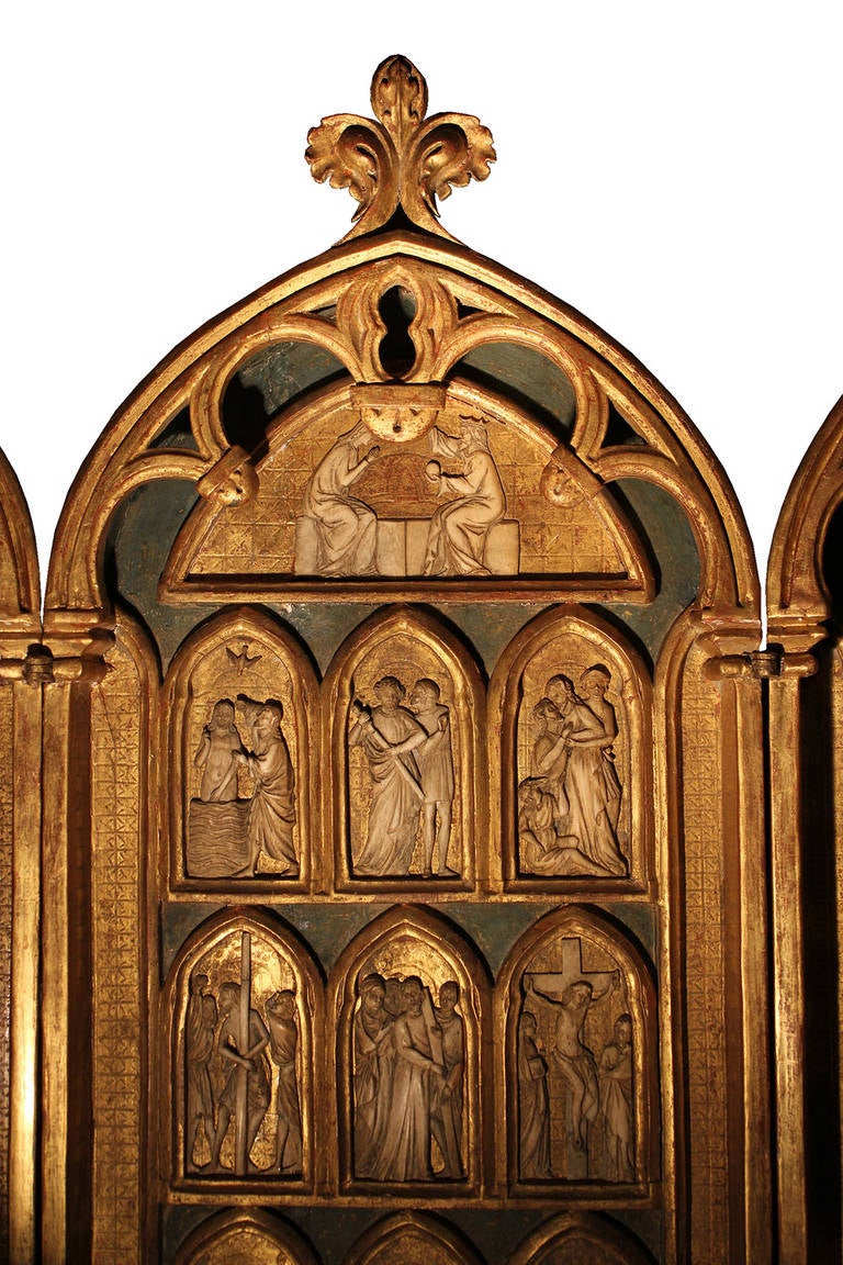 A Magnificent Late 16th Century - Early 17th Century Giltwood, Ivory and Polychrome Triptych, the three panels depicting the story of Christianity in twenty-one vignettes, each with ivory figures depicted against gold and polychrome grounds, with
