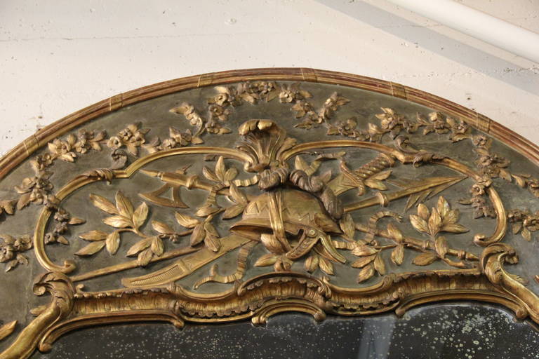 A Chateau Scaled 18th Century French Polychrome and Parcel Gilt Trumeau Mirror, with a single antiqued mirror plate, and the frame embellished with gilded fruited vines with the top portion centered by a neoclassical 
