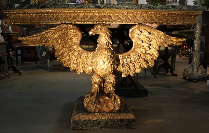 A Rare and Important Pair of English George II Palladian Giltwood Console Tables retaining their original rectangular verde issori marble tops above conforming friezes with carved vitruvian scrolls raised on pedestals of Jupiter's eagles, standing