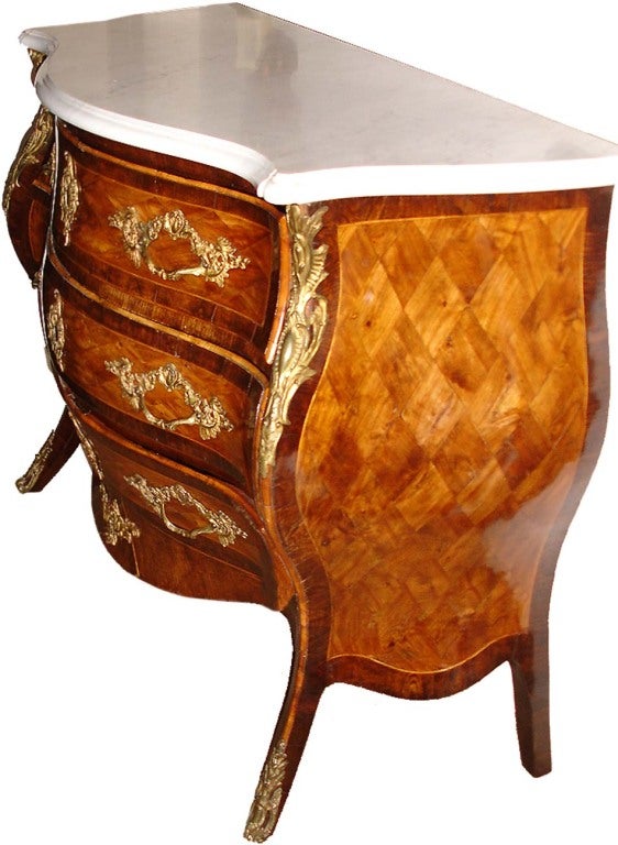 A rare 18th century Italian Louis XV arbalette bombé commode featuring harlequin palisander marquetry bordered by satinwood stringing and rosewood crossbanding, an unusual lifted skirt, the original hardware and Carrara marble top, three drawers,