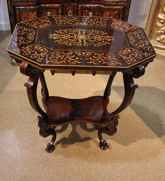 A 19th century Florentine ebony and marquetry side table, the octagonal top inlaid with satinwood filigree and flowers raised on exaggerated shaped legs accented with satinwood stringing and connected by a conforming under tier.
