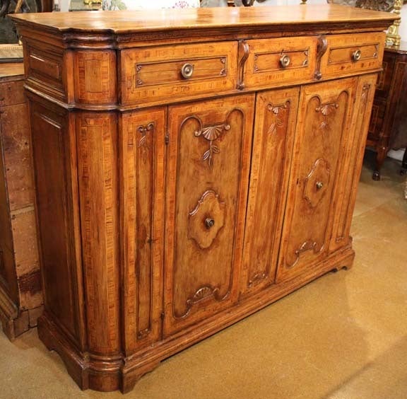 An 18th century Baroque Tuscan walnut Credenza with two large lower cabinets below three pull-out drawers, with the whole decorated with fielded panels, later period-appropriate brass hardware and raised on shaped bracket feet.