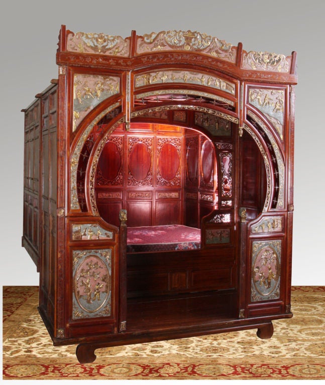 Late 19th century Chinese wedding bed with pierce carved crest and parcel gilt relief carved figural panels surrounding the facade.  The interior is divided into two areas - one for placing one's personal items and the other for sleeping, with