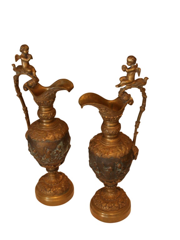 Large pair of Victorian classically inspired ewers having putti adornments and foliate embellishments. Stamped 