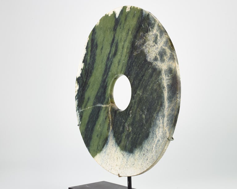 A large nephrite jade bi-disc with some calcification near the edges showing different layers of light and dark green color.