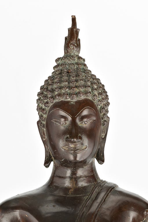 A tall figure of Buddha Shakyamuni standing with one leg in front of the other, wearing a light garment revealing one shoulder, the left hand in Vitarka mudra with the thumb and index finger forming a circle symbolizing the Wheel of Law, an