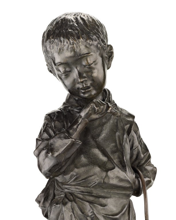 A large and charming bronze sculpture of a young boy standing, a large ring hanging from his right forearm, looking down at a dog seated at his feet. Signed on the base in cursive signature 
