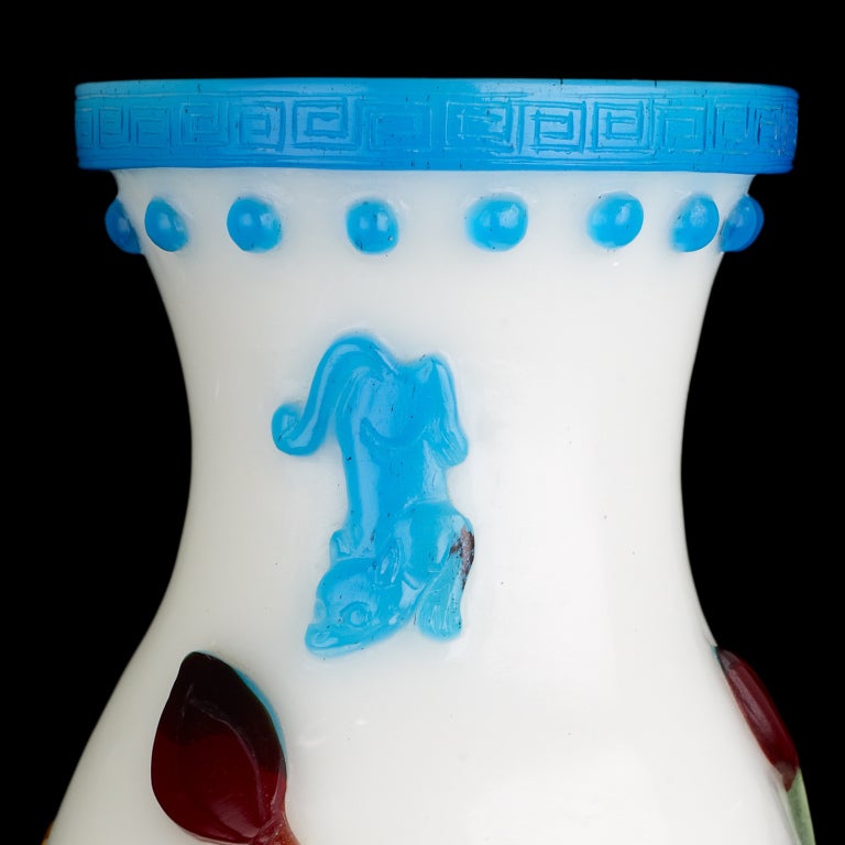 A translucent white vase of baluster form with a broad cylindrical neck, decorated with transparent glass overlays of turquoise, pale green, red and yellow-brown depicting lotus growing from scrolling waves, the mouth bordered with a band of incised